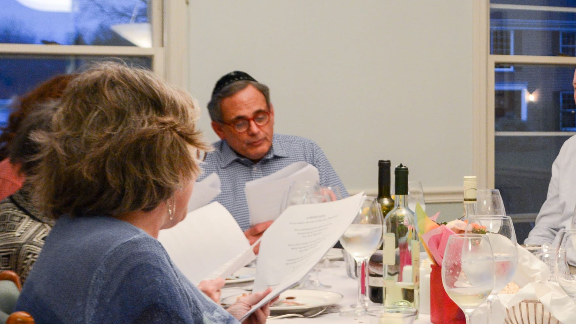 A man sits and reads to a table during a passover sedar.